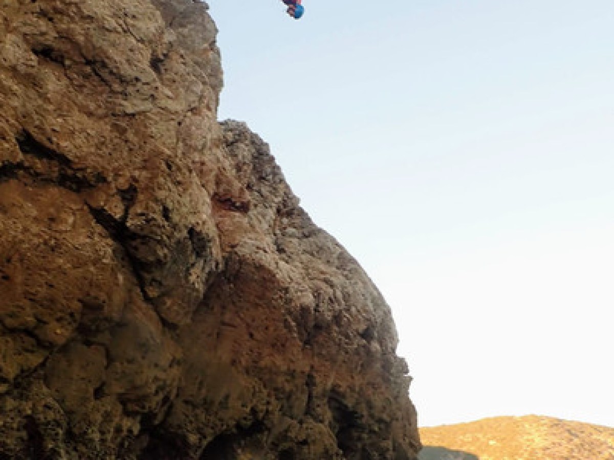 a man flying through the air on a rock near the ocean