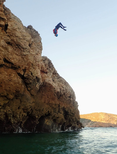 a man flying through the air on a rock near the ocean