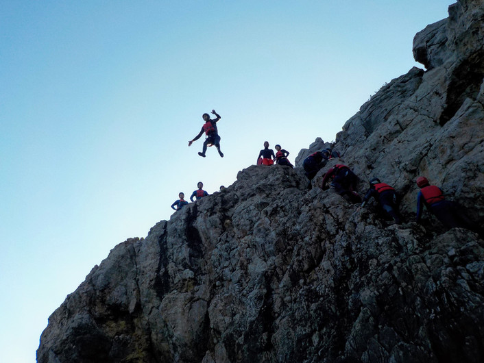 a man flying through the air on a rocky hill