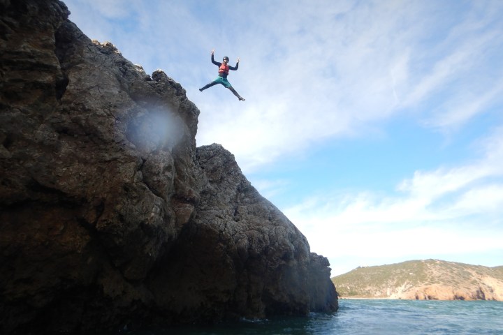 a man flying through the air on a rock near the ocean