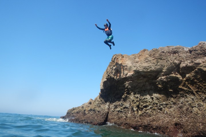 a man flying through the air on a rock