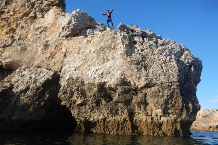 a man flying through the air on a rock next to water